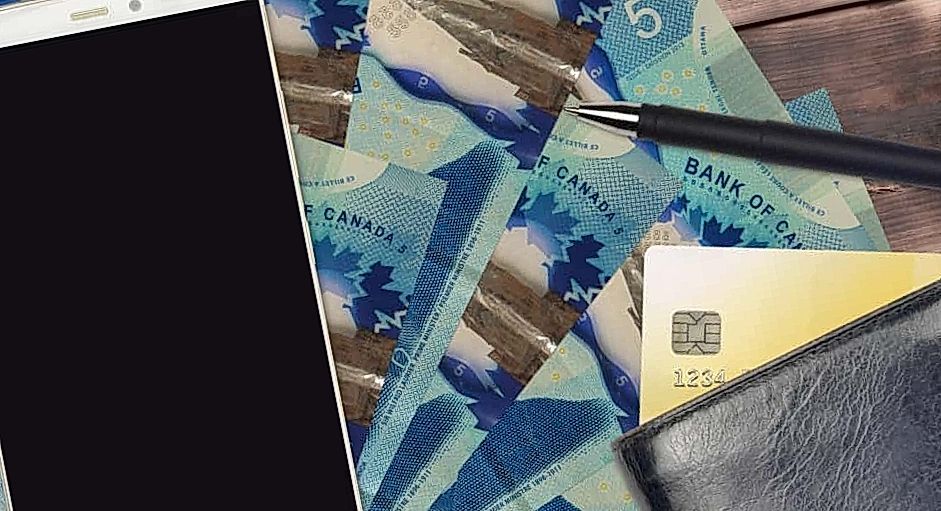 five canadian dollars with smartphon lying on the table